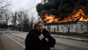 Mulher com roupa preta foge de região atingida por bombardeio