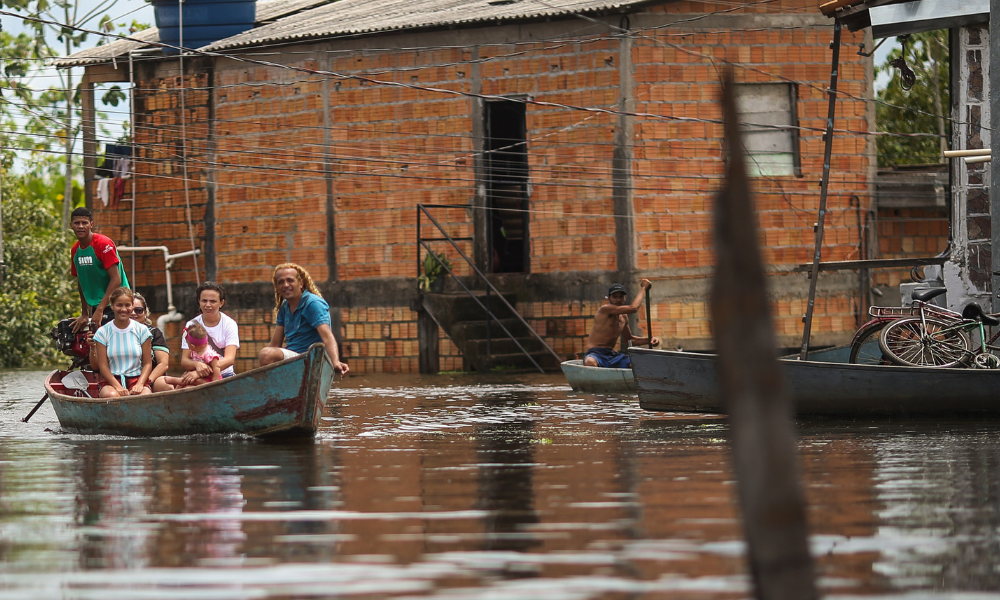 Pessoas tentam se locomover de barco durante enchente em bairro de Marabá