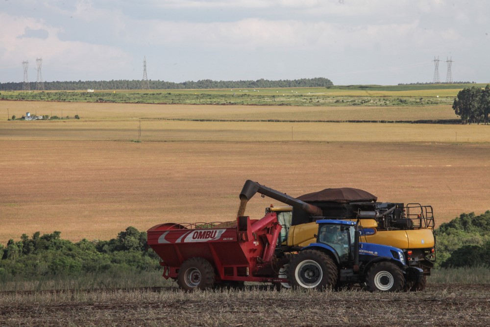 Trator realiza colheita de soja em propriedade rural