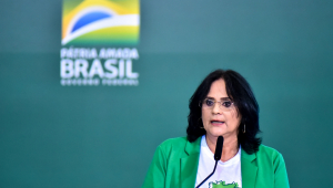 Ministra Damares Alves falando no microfone; ao fundo, o slogan do governo Bolsonaro: 'Pátria Amada, Brasil'