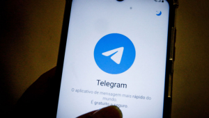 Mão feminina segura celular aberto no aplicativo Telegram
