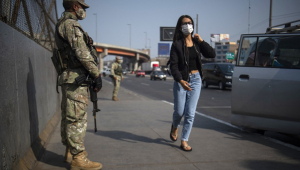 Mulher anda próxima a soldado em avenida de Lima