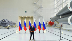 Com seis bandeiras da Rússia atrás, em um saguão, O presidente russo, Vladimir Putin, discursa durante sua visita ao cosmódromo de Vostochny
