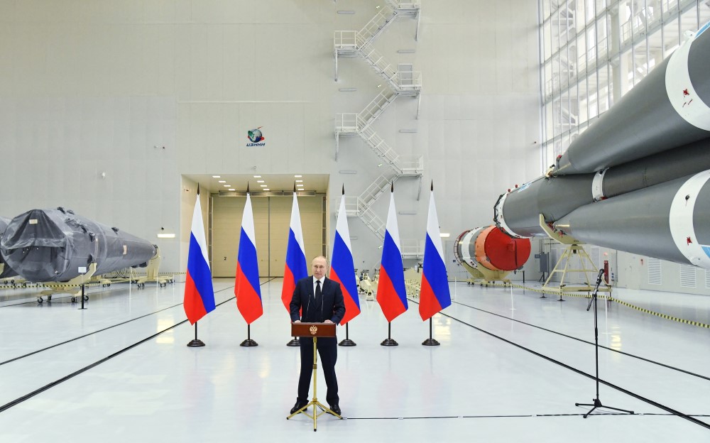 Com seis bandeiras da Rússia atrás, em um saguão, O presidente russo, Vladimir Putin, discursa durante sua visita ao cosmódromo de Vostochny