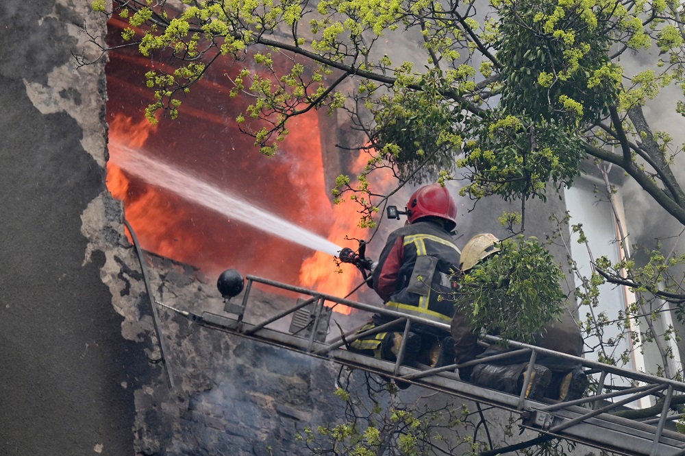 Bombeiros tentam apagar um incêndio em um prédio residencial após bombardeio no centro de Kharkiv