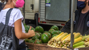 Cliente de máscara observa frutas e legumes em barraca de fruta