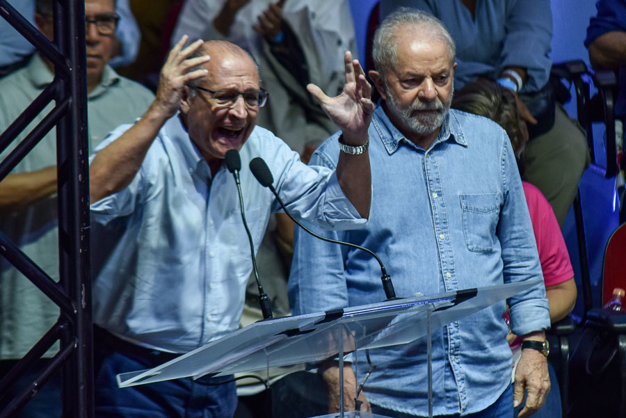 Geraldo Alckmin berrando com as mãos para o alto ao lado de Lula