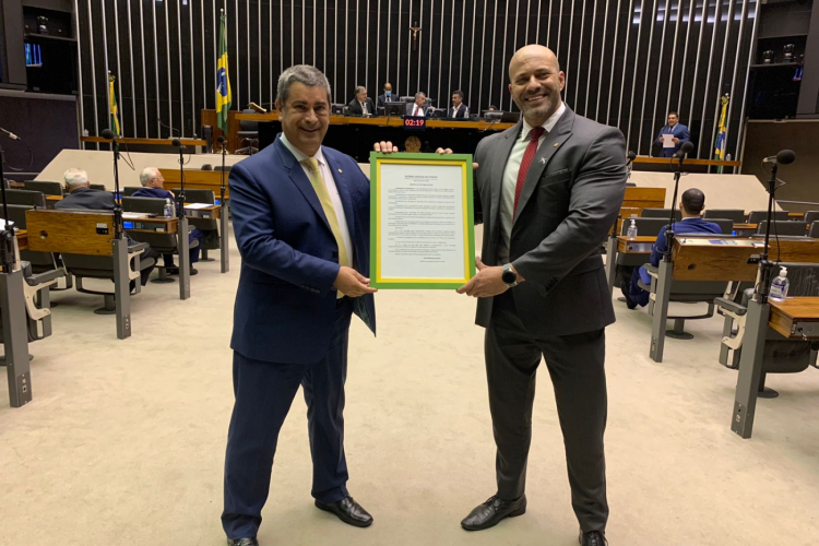Os deputados Coronel Tadeu e Daniel Silveira segurando um quadro com o indulto da graça concedido pelo presidente Jair Bolsonaro