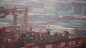 Trabalhadores em um guindaste sobre contêineres no porto de Xangai, em um dia com bastante neblina