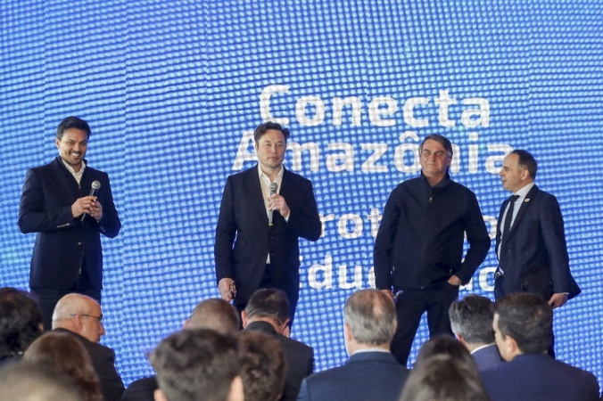 Foto mostrando o presidente Jair Bolsonaro (2-R), seu ministro da Comunicação Fabio Faria (E) e CEO, e o engenheiro-chefe da SpaceX, Elon Musk (2-L), no evento Conecta Amazônia em Porto Feliz