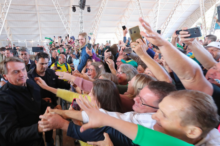 Bolsonaro é tietado por centenas de apoiadores, que levantam as mãos e apontam os celulares para o presidente