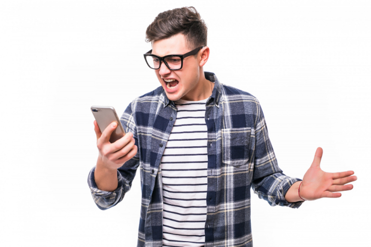 Jovem de óculos segura o celular enquanto faz cara de bravo