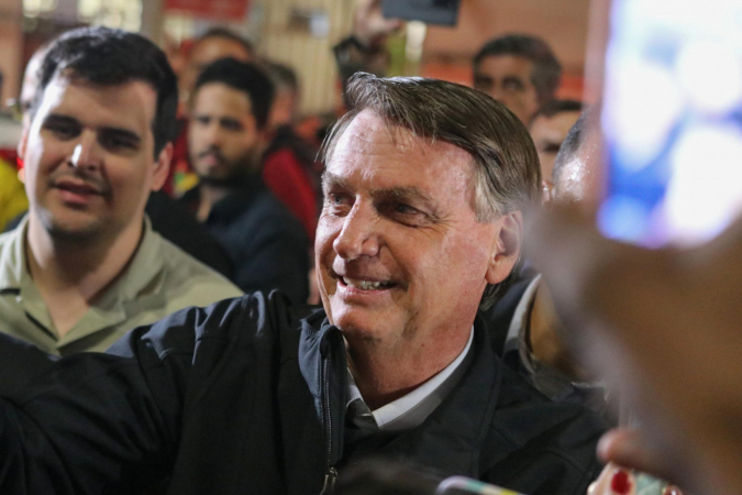 Bolsonaro cumprimenta apoiadores enquanto é acompanhado por outras pessoas