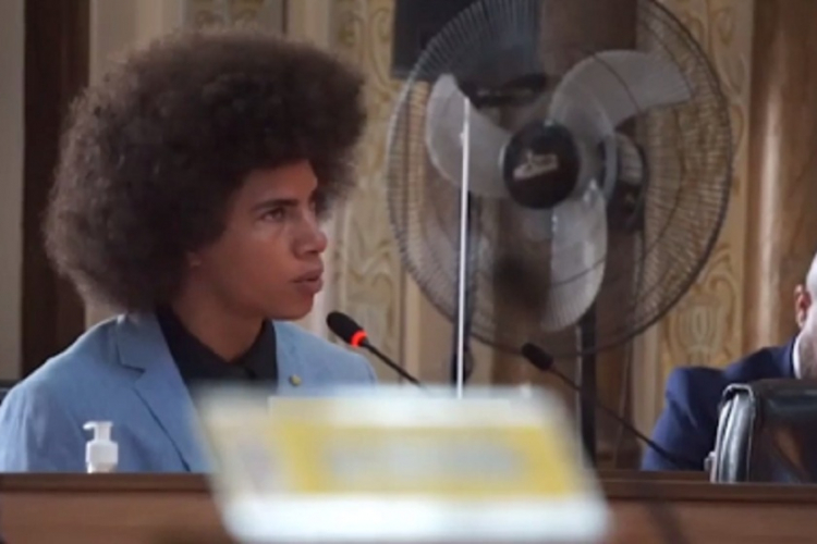 Renato Freitas: homem negro com black power, sentado, fala em microfone na Câmara Municipal de Curitiba