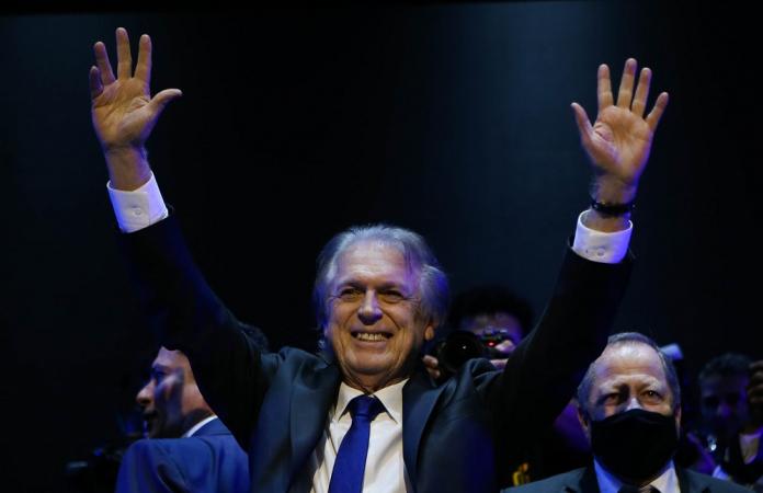 Luciano Bicar de terno, gravata e braços abertos, sorrindo, durante o lançamento de sua pré-candidatura