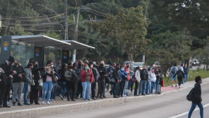 Dezenas de pessoas aglomeradas em um ponto de ônibus de São Paulo