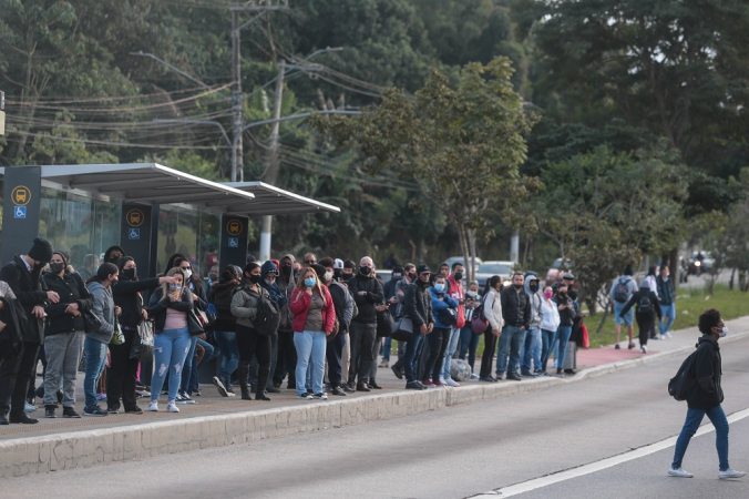 Dezenas de pessoas aglomeradas em um ponto de ônibus de São Paulo