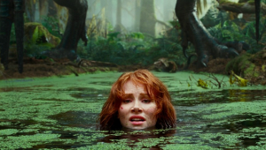 A personagem de Bryce Dallas Howard na lama, só com a cabeça para fora, desesperada com a iminente chegada de um dinossauro, do qual só se vê os pés