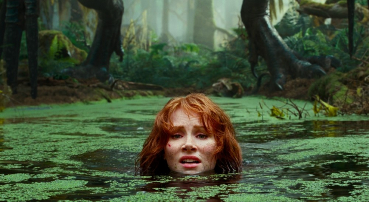 A personagem de Bryce Dallas Howard na lama, só com a cabeça para fora, desesperada com a iminente chegada de um dinossauro, do qual só se vê os pés