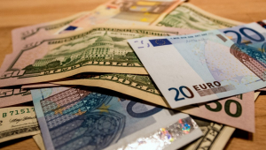 Notas de dólar e euro espalhadas sobre uma mesa