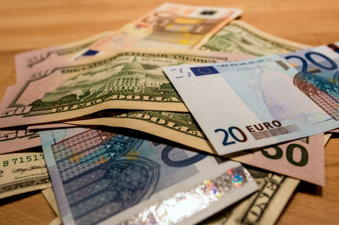 Notas de dólar e euro espalhadas sobre uma mesa