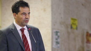 O ministro Adolfo Sachsida, vestido com trajes sociais, fala em pé em frente a um microfone