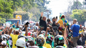 Em meio a motociclistas, a maioria de amarelo, Bolsonaro, de jaqueta preta, acena para apoiadores