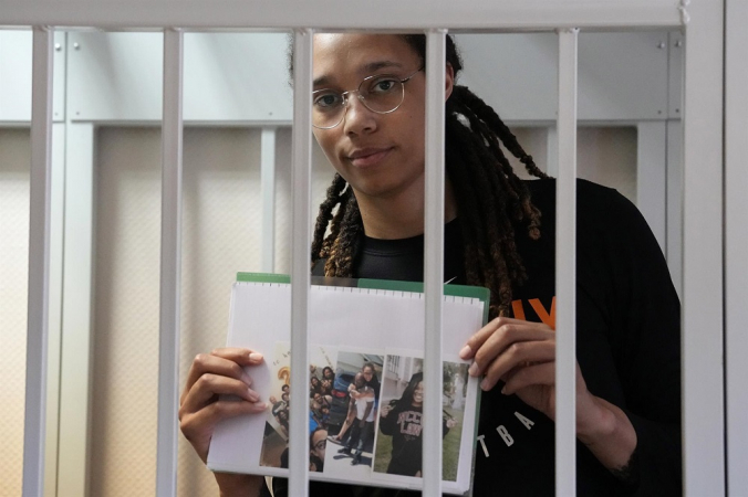 A estrela da WNBA e duas vezes medalhista de ouro olímpica Brittney Griner segura imagens em uma gaiola em um tribunal antes de uma audiência