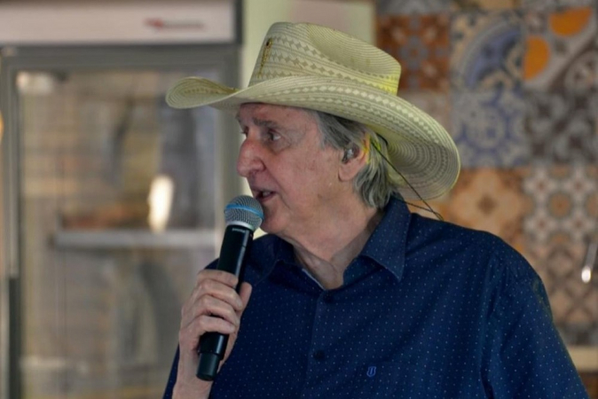 Com chapéu e camisa azul de manga curta, Sérgio Reis fala ao microfone