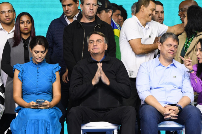 Michelle Boslonaro, de azul, Jair Bolsonaro, de preto, e Tarcísio de Freitas, de azul claro e calça jeans, todos sentados