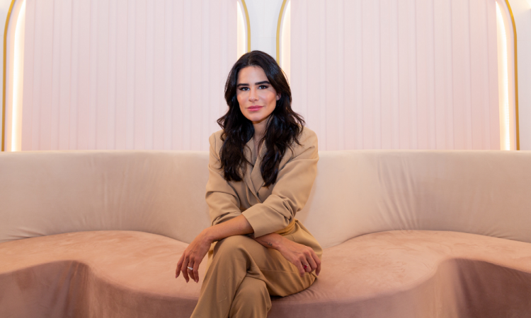 A empresária Natalia Martins, toda de rosa, sentada em um sofá