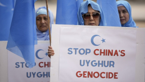 Mulheres que apoiam o Movimento de Despertar Nacional do Turquistão Oriental se reúnem em frente à Casa Branca e exibem cartazes com os dizeres "parem o genocídio uigur"