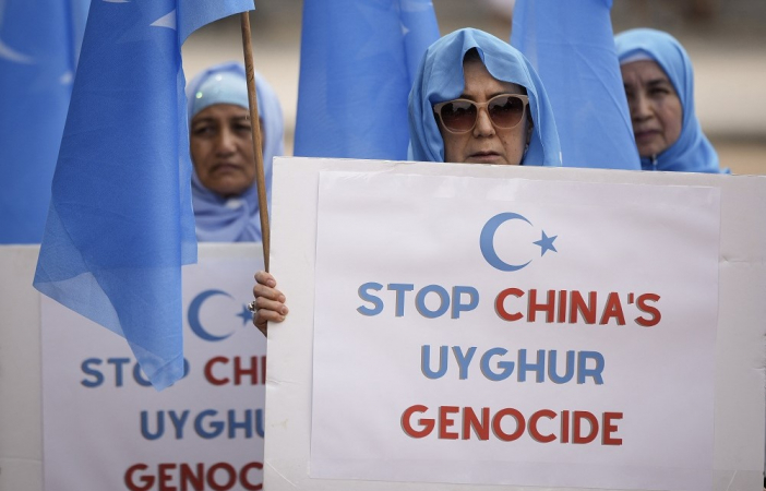 Women who support the East Turkistan National Awakening Movement gather in front of the White House and hold up posters that read 
