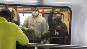 Foto tirada de fora do metrô mostra dois homens usando máscara dentro do vagão