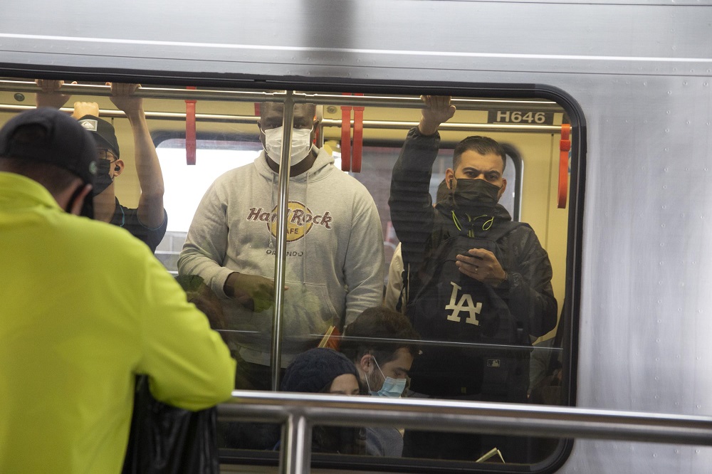 Foto tirada de fora do metrô mostra dois homens usando máscara dentro do vagão