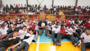 Vampeta no centro da quadra, segurando bola, cercado por alunos do Colégio Amorim