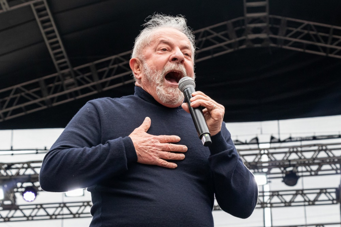 Lula com blusa fina preta, microfone na mão esquerda e gritando no palco do Anhangabaú