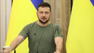 Zelensky de camiseta em frente a duas bandeiras da Ucrânia