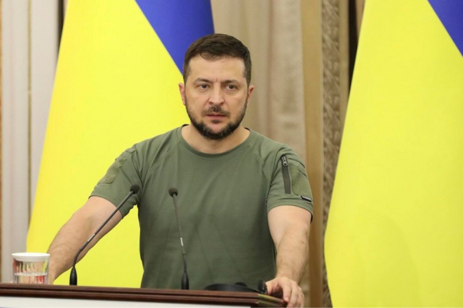 Zelensky de camiseta em frente a duas bandeiras da Ucrânia