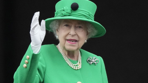 Rainha Elizabeth II acena para o público de dentro do Palácio de Buckingham
