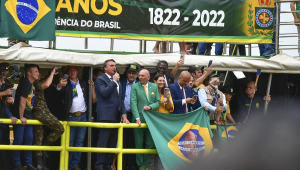 Bolsonaro em um cercadinho alto, com proteção amarela à sua frente Luciano Hang à sua esquerda e mais uma dezena de apoiadores ao redor, fala durante ato de 7 de setembro no Rio
