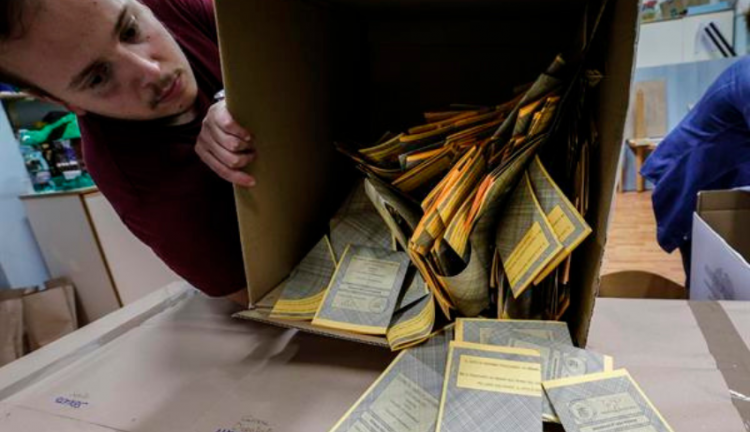 Homem virando caixa com votos das eleições na Itália