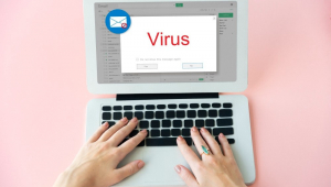 Mãos digitam em notebook e tela mostra e-mail com um cartão escrito vírus