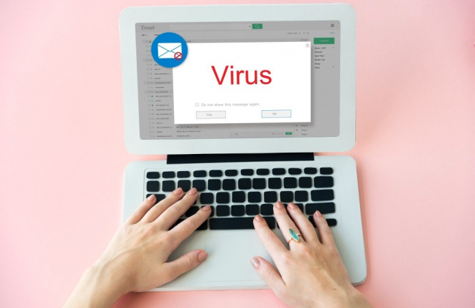 Mãos digitam em notebook e tela mostra e-mail com um cartão escrito vírus