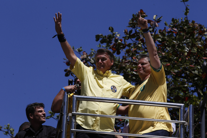 Homens de camisa amarela acenam para a população