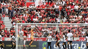 Lance do jogo feminino entre Internacional e Corinthians com torcida colorada ao fundo, atrás do gol