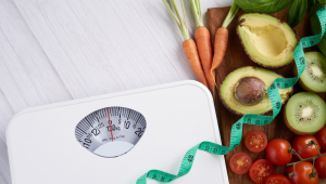 Foto conceitual sobre perda de peso, com balança, fita métrica, frutas e legumes