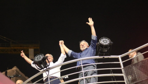 LUla e Geraldo Alckmin de mãos dadas para cima em um palanque