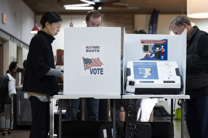 Americano vota em sala de votação com ícone gráfico da bandeira do país na lateral da cabine