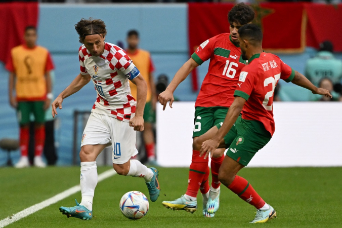 Com a bola dominada, Modric tenta passar pr dois jogadores marroquinos